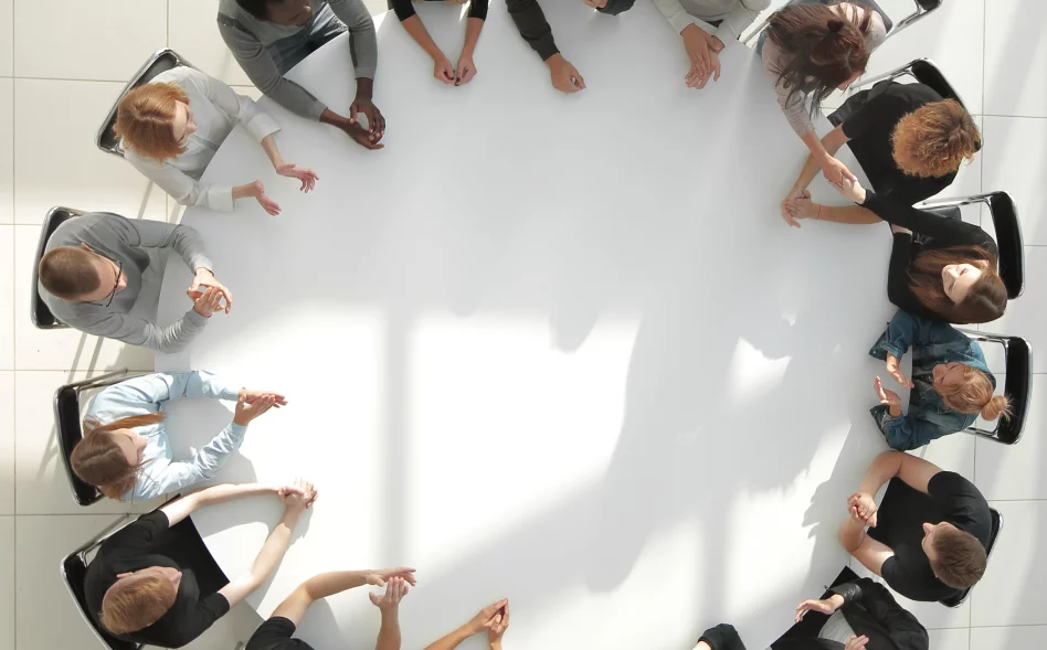 top-view-young-people-shaking-hands-round-table-meeting-1